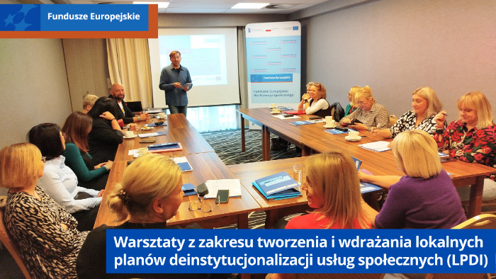 Uczestnicy szkolenia siedzą przy stołach. Z przodu ekran i prowadzący szkolenie