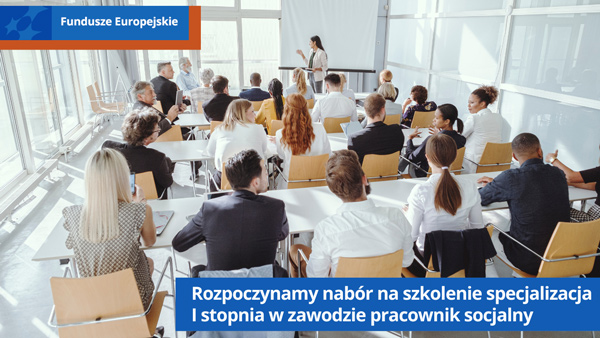 Uczestnicy szkolenia siedzą w ławkach. Z przodu prowadzący szkolenie stoi przy tablicy