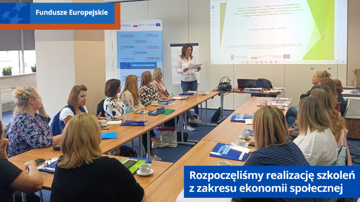 Uczestnicy szkolenia siedzą przy stołach i słuchają wykładu