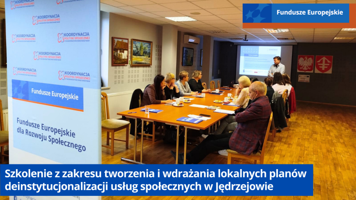 Uczestnicy szkolenia siedzą przy dużym stole. Na drugim planie ekran z prezentacją i prowadzący szkolenie