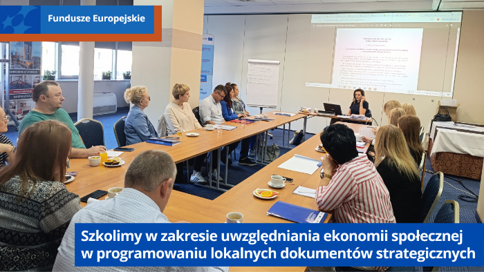 Uczestnicy szkolenia siedzą przy stołach i słuchają wykładu