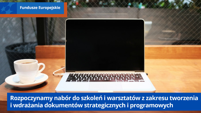 Laptop na biurku, po lewej stronie kubek z kawą.