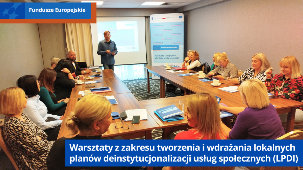 Uczestnicy szkolenia siedzą przy stołach. Z przodu ekran i prowadzący szkolenie