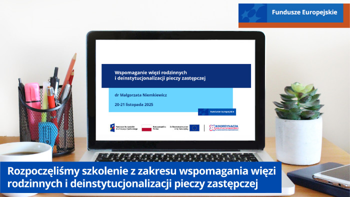 Laptop na biurku. Obok stoi kubek z kawą i kwiatek w doniczce. Na ekranie laptopa napis Wspomaganie więzi rodzinnych i deinstytucjonalizacji pieczy zastępczej dr Małgorzata Niemkiewicz