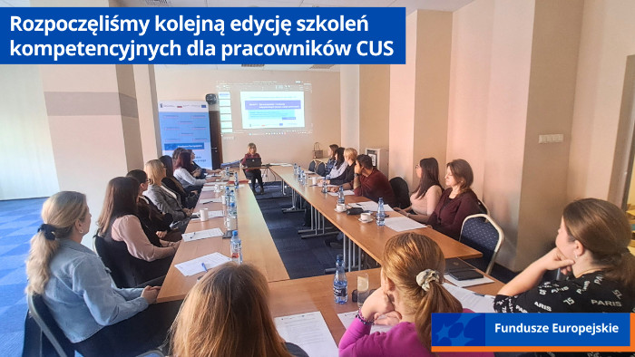 Uczestnicy szkolenia siedzą przy stołach. W oddali prowadząca szkolenie